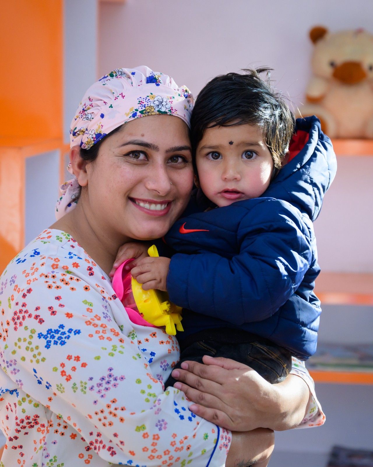 dentist in a heart-print cap warmly hugging a young patient
